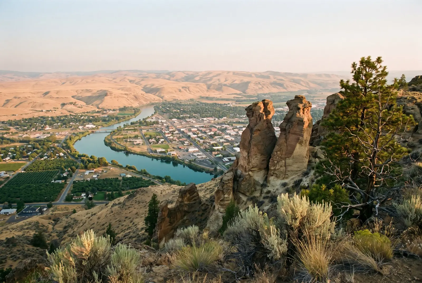 View over the Wenatchee Valley from a sagebrush ridge, the river curving past town and orchards